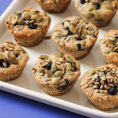 PACKD Vegan Banana and Blueberry Muffins in a white tray on a purple tabletop