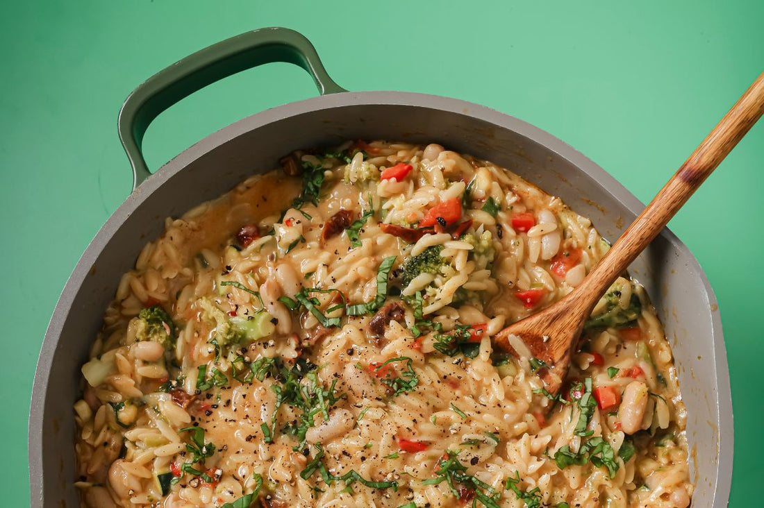 PACKD One pan creamy vegetable orzo in a pot with a wooden spoon.