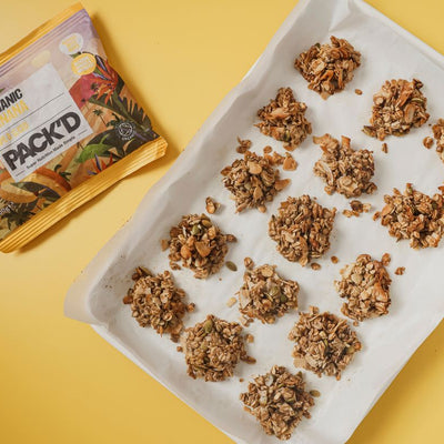 A tray of 15 granola clusters, next to a packet of PACKD frozen organic bananas