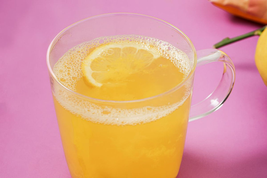 A glass of warm ginger and garlic with a cut lemon on top