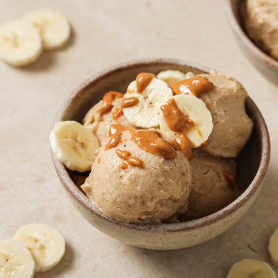 PACK'D's 3 ingredient Creamy Vegan Ice Cream in a bowl with banana slices on the table