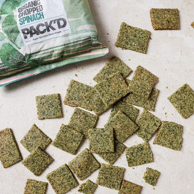 Pack show of PACK'D Spinach Crackers with crackers spread in from of the packet.