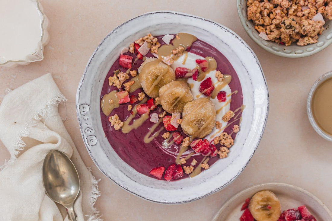 A vibrant organic acai smoothie bowl topped with fresh strawberries, sliced banana, and granola, representing a healthy January sugar reset.