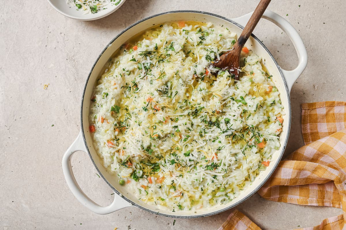 Overhead view of a creamy Baked Lemon and Herb Risotto served in a casserole dish, speckled with green PACK'D Petit Pois and fresh dill.