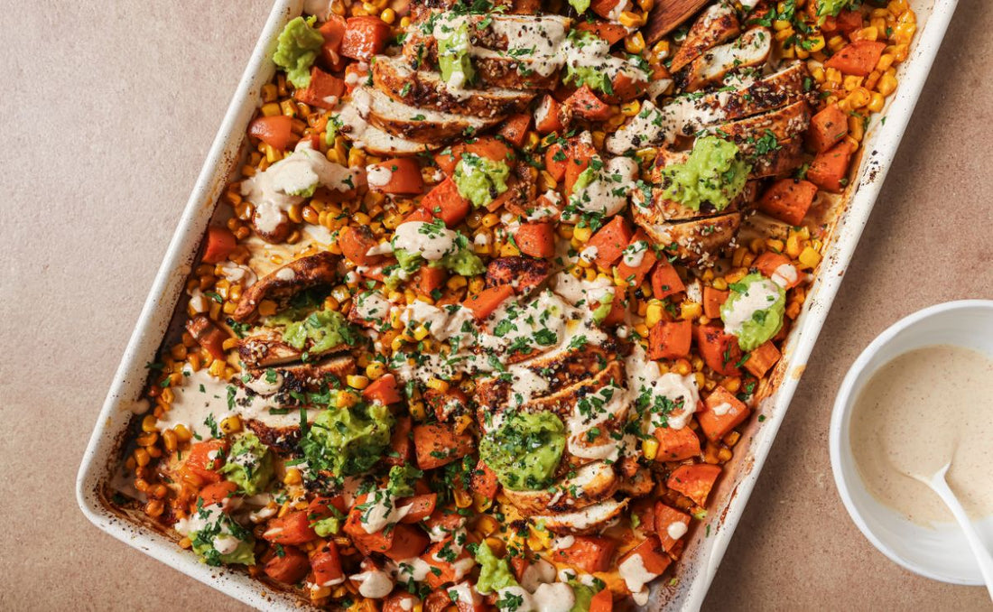 Chipotle chicken traybake with sliced spiced chicken, roasted PACK'D Organic Sweet Potato, PACK'D Organic Sweetcorn and mashed PACK'D Organic Avocado, drizzled with yoghurt dressing and topped with fresh herbs and sesame seeds