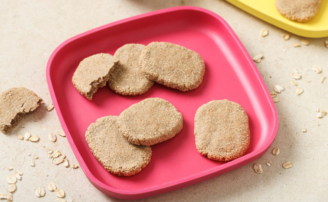 Homemade banana oat teething biscuits on a pink children's plate, made with PACK'D Organic Banana — a healthy, no-added-sugar snack for babies