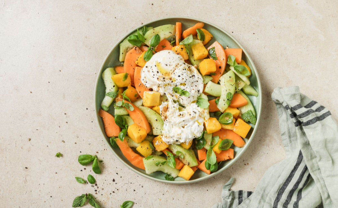 Melon, burrata and mango salad on a green plate with basil and mint, made with PACK'D Organic Frozen Mango
