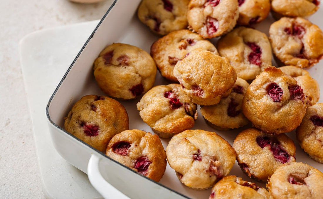 A baking tray filled with golden mini strawberry yoghurt muffins studded with pieces of PACK'D Organic Strawberries, fresh from the oven