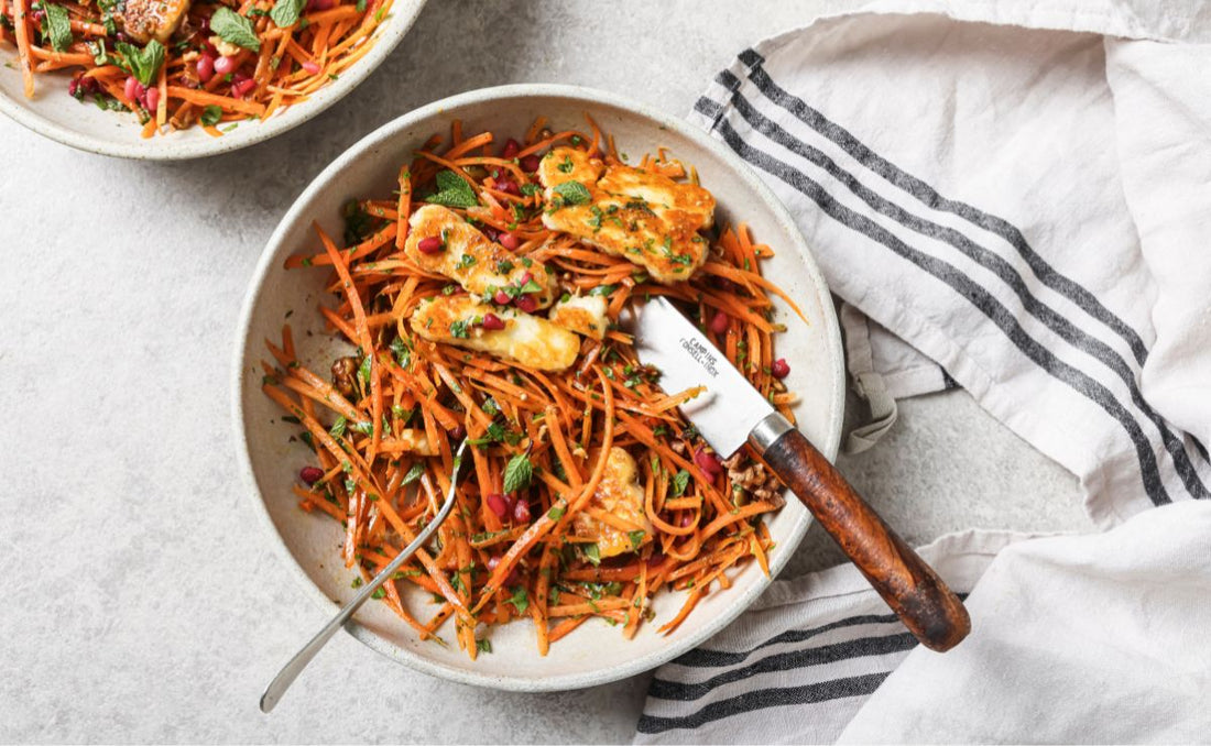 Moroccan carrot salad with golden pan-fried halloumi, julienned carrots, toasted walnuts, fresh mint and PACK'D Organic Pomegranate seeds in a ceramic bowl