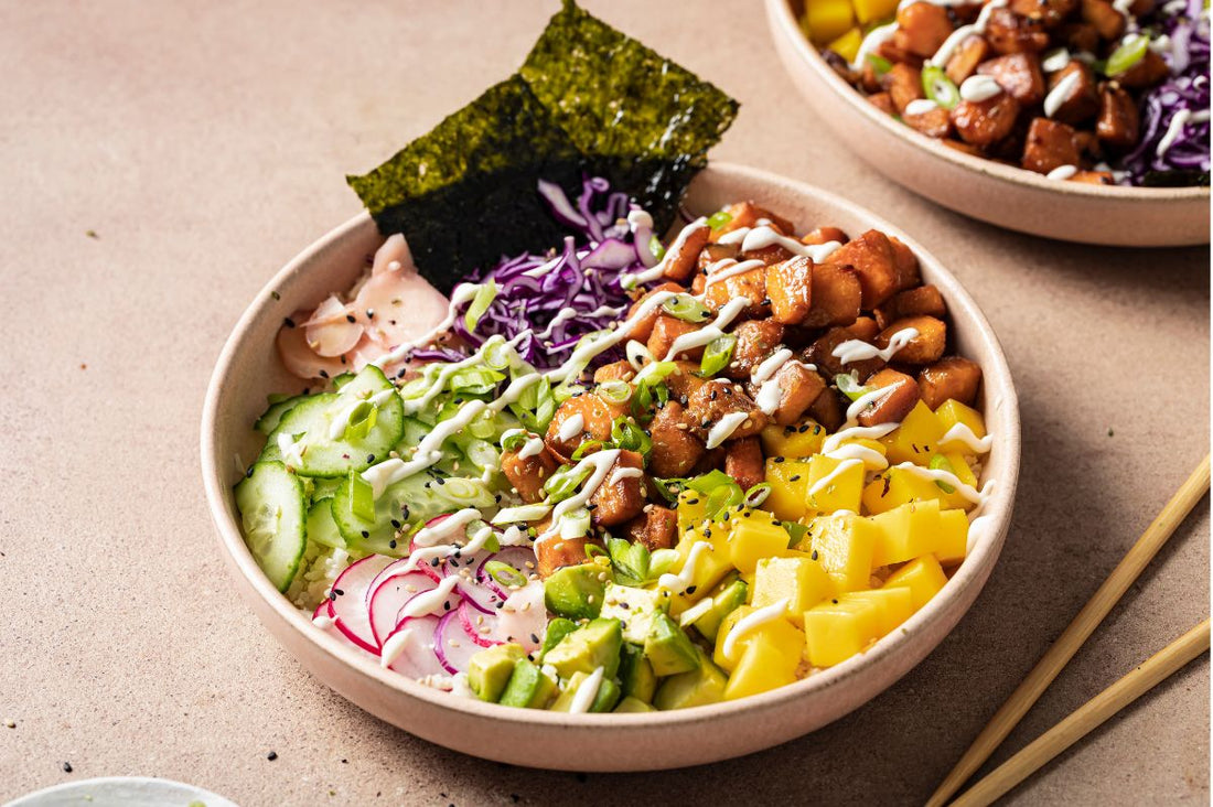 Two Sweet Potato and Cauliflower Rice Poke Bowls topped with diced mango, avocado, cucumber, and a drizzle of citrus mayo, featuring PACK'D organic sweet potatoes.